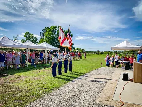 A group of people are standing in a field holding flags.