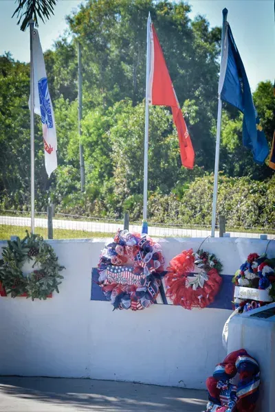 A white wall with flags and wreaths on it.