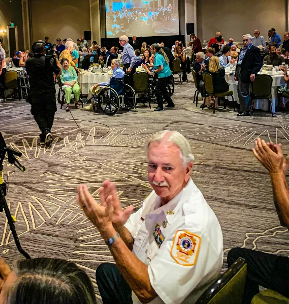 A group of people are clapping in a large room