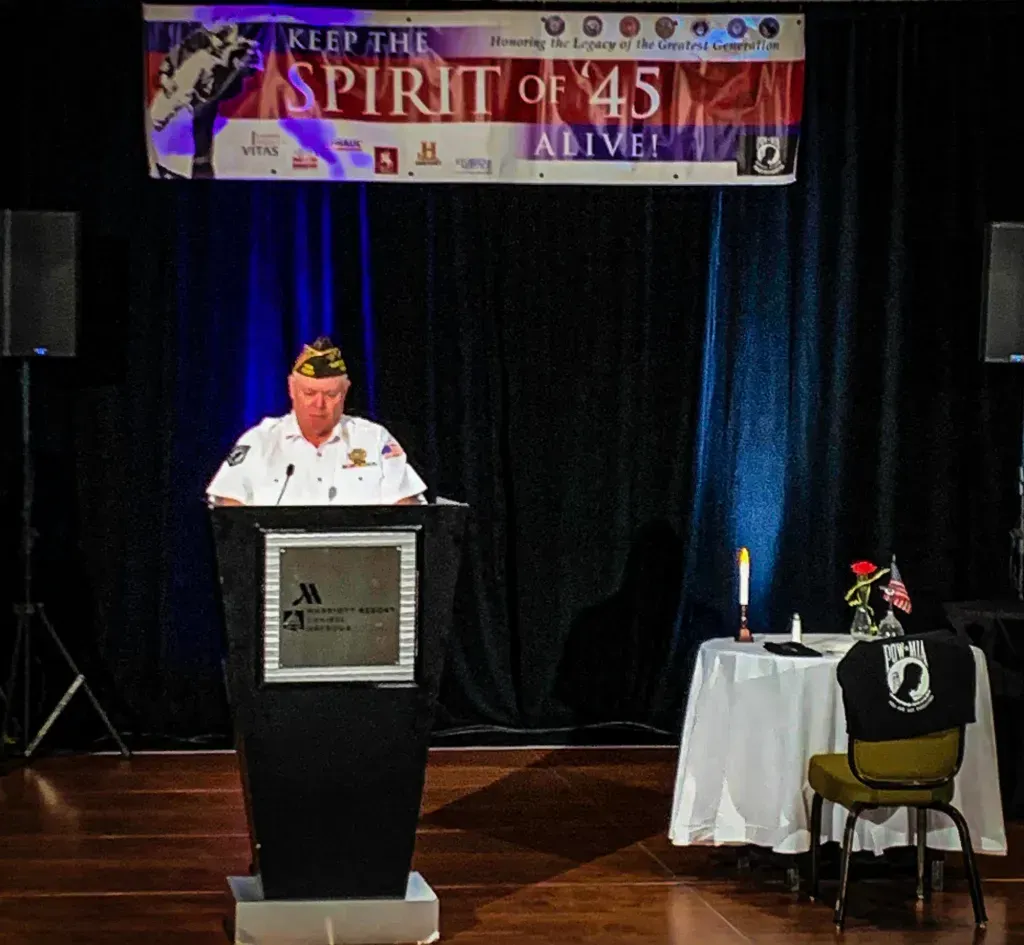 A man stands at a podium in front of a banner that says 