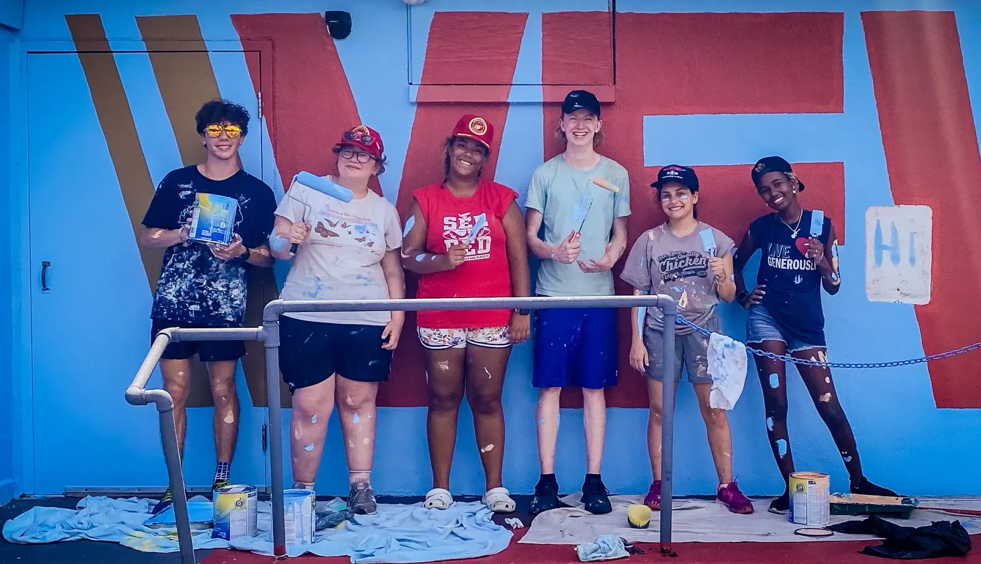 A group of people are standing in front of a blue wall.