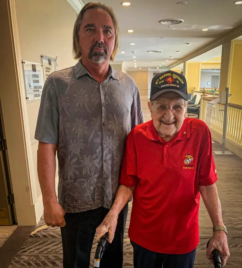 Two men are standing next to each other in a hallway.