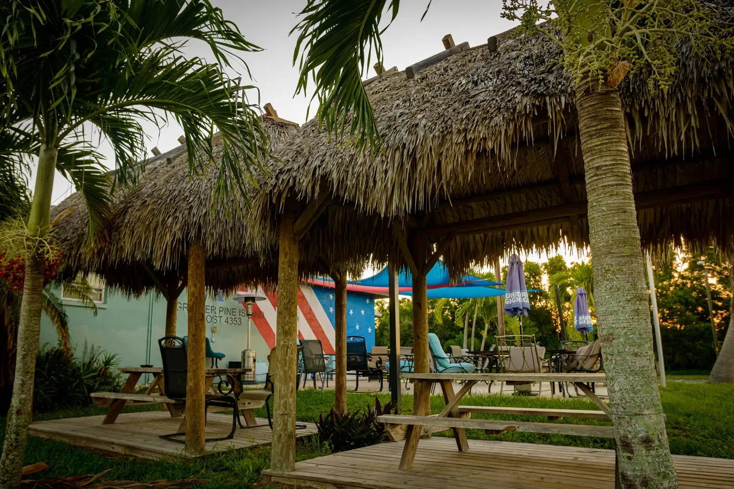 A picnic area with thatched roofs and tables and chairs