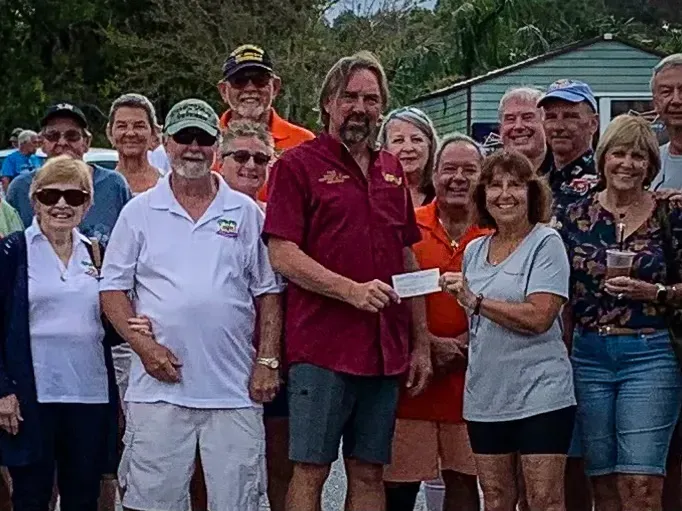 A group of people standing around a man holding a check.