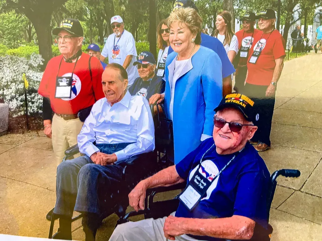 A group of people are standing around a man in a wheelchair.