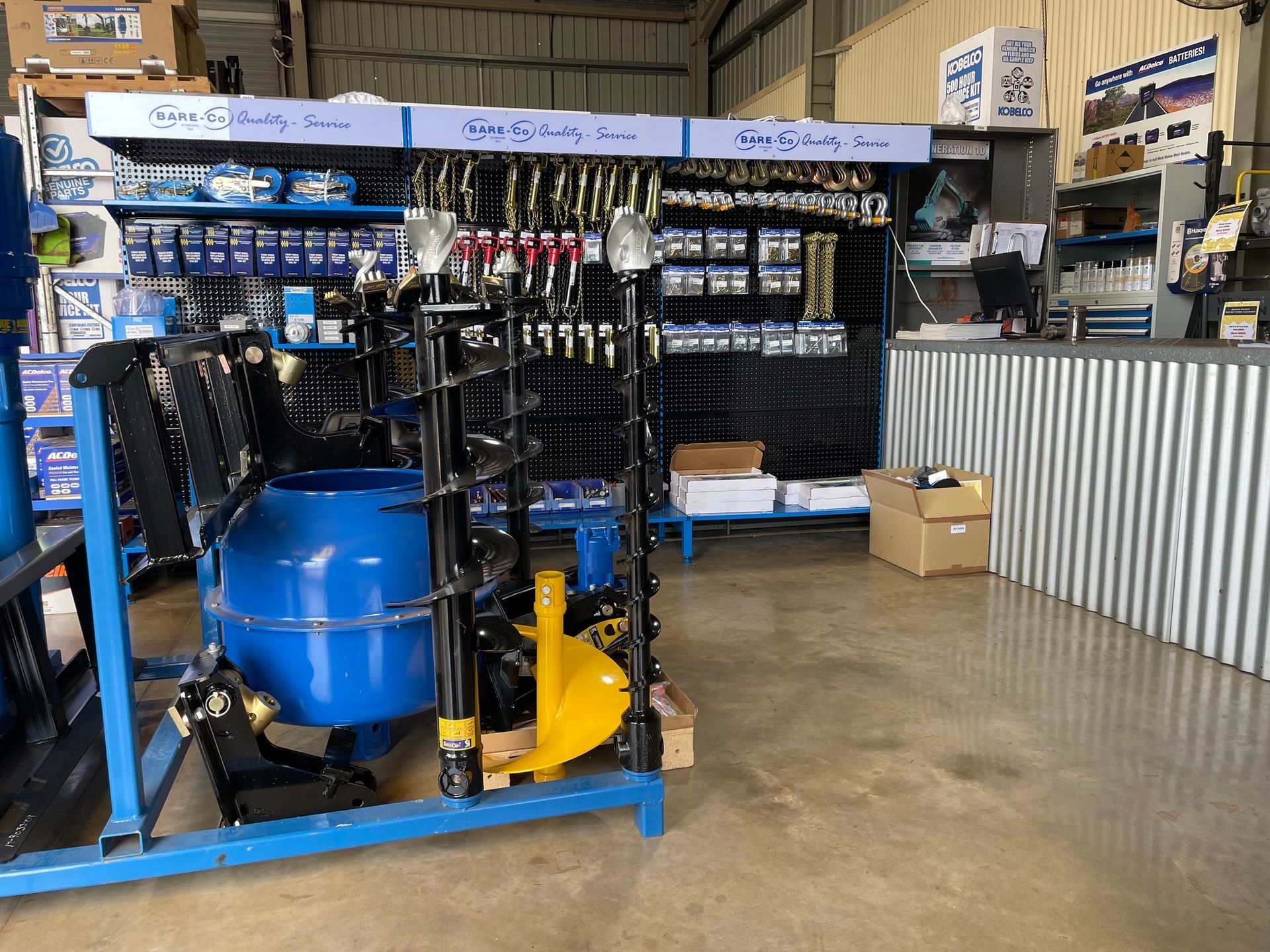 Inside a hardware store; blue display rack with a cement mixer and augers, tools, and shelves of supplies — Forecast Machinery in Yarrawonga, NT