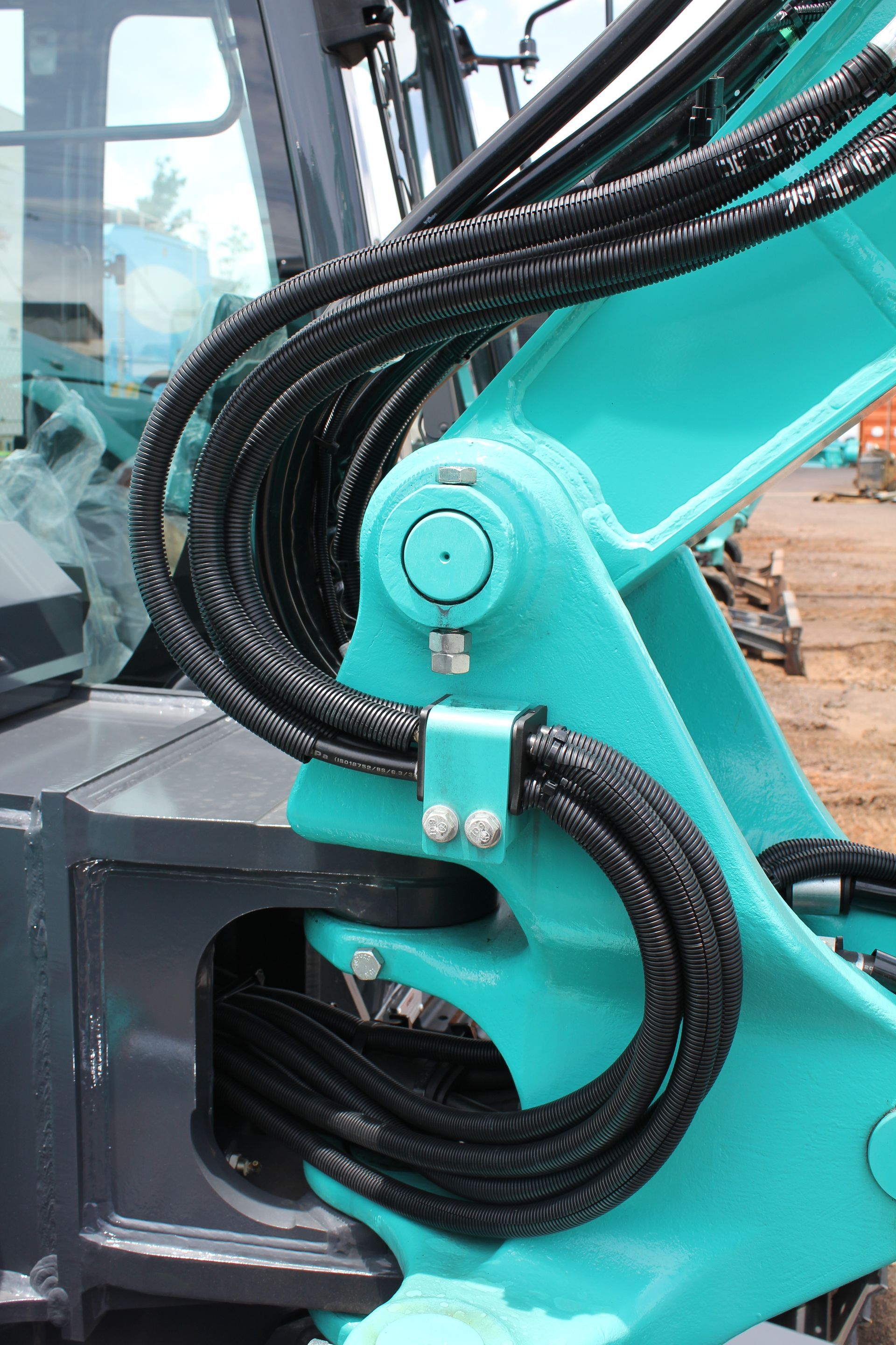 Turquoise excavator arm with black hoses, bolted, in an outdoor setting — Forecast Machinery in Yarrawonga, NT