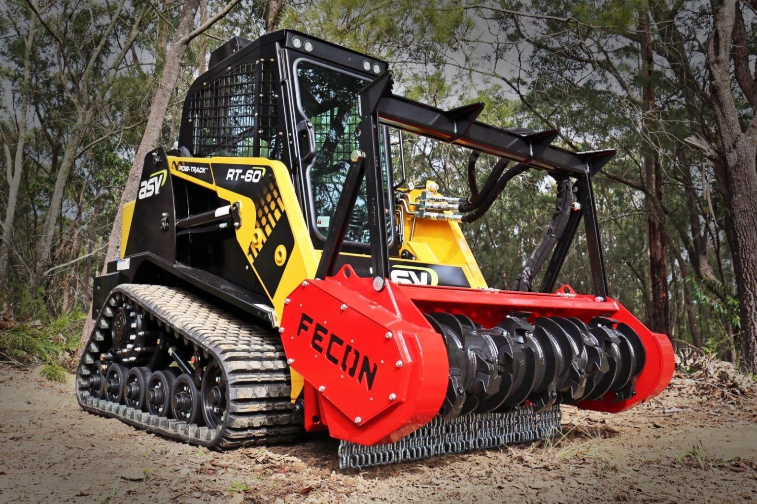 Yellow and black tracked skid steer with red brush cutter attachment, in a wooded area — Forecast Machinery in Yarrawonga, NT