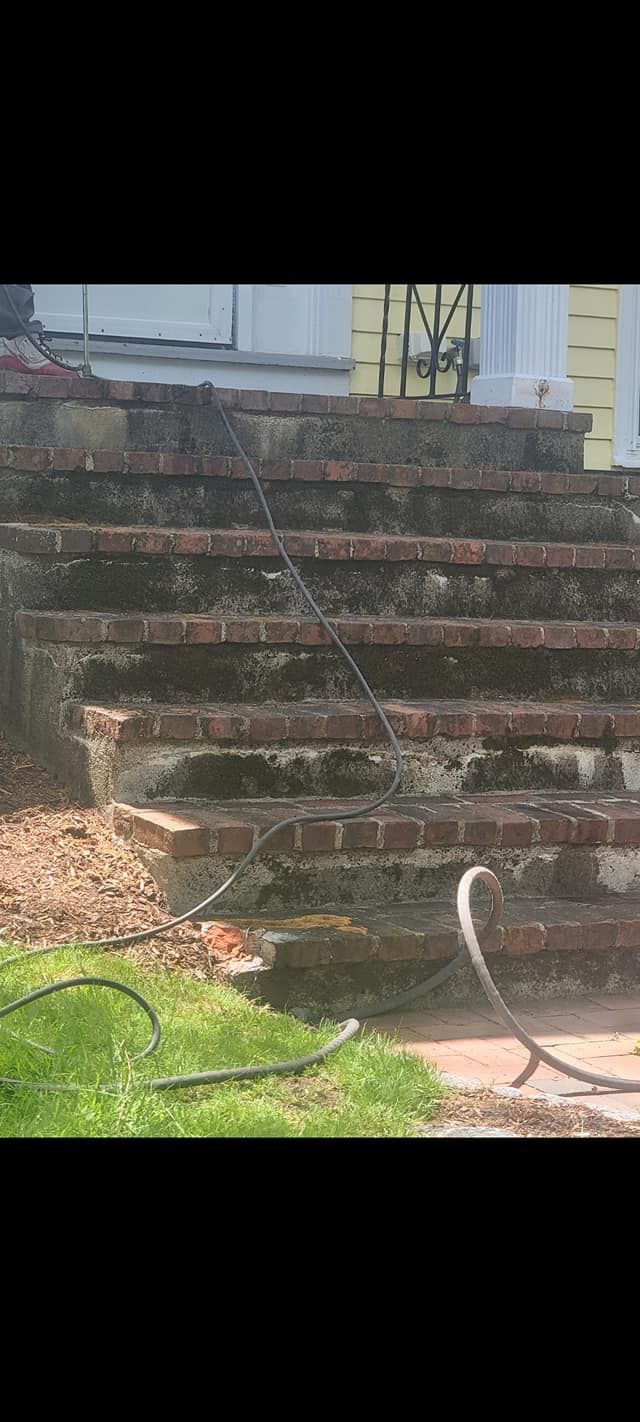 Brick stairs covered in moss. A hose is on the steps and in the grass.