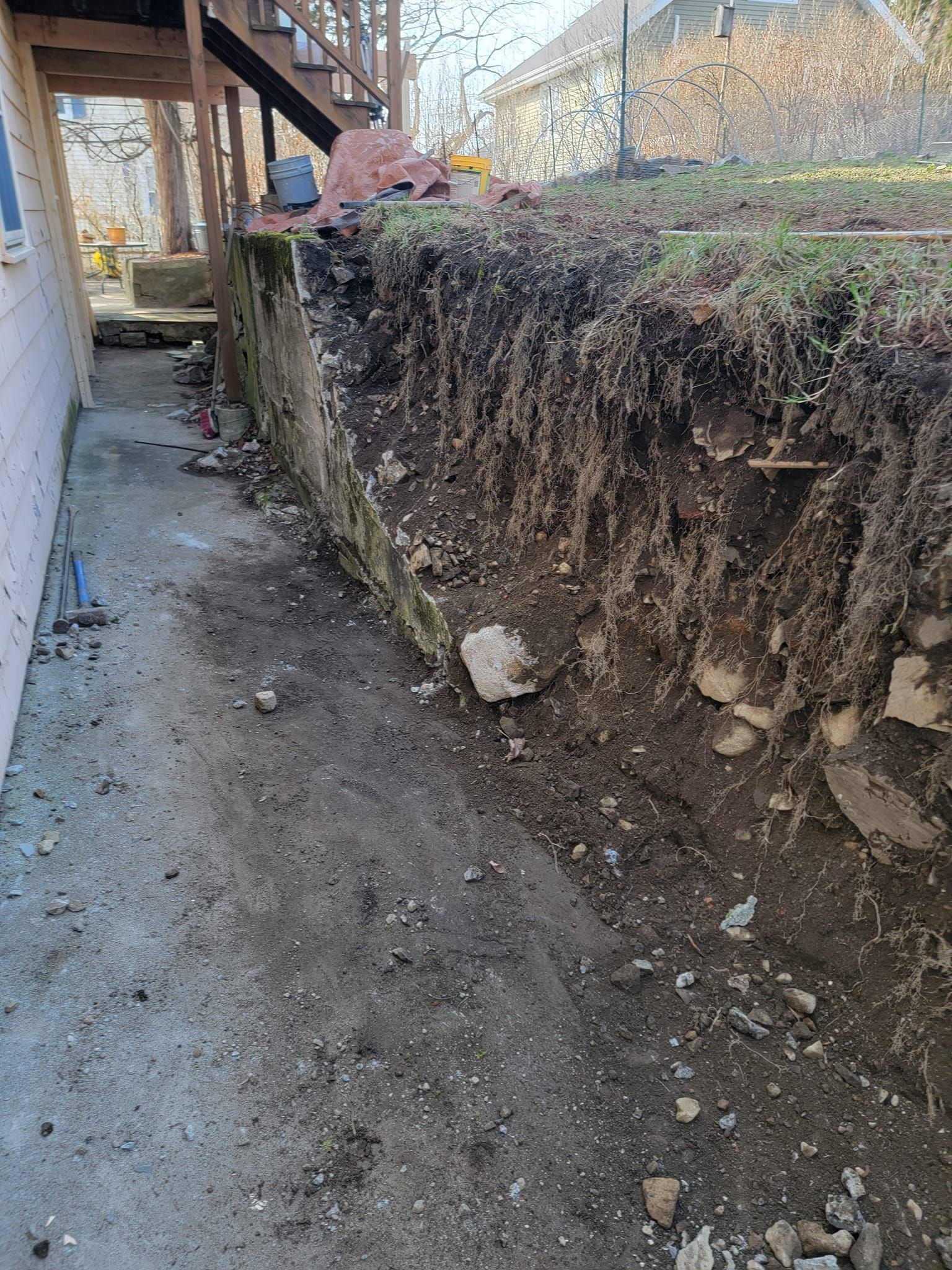 Concrete walkway next to excavated soil, under a deck.