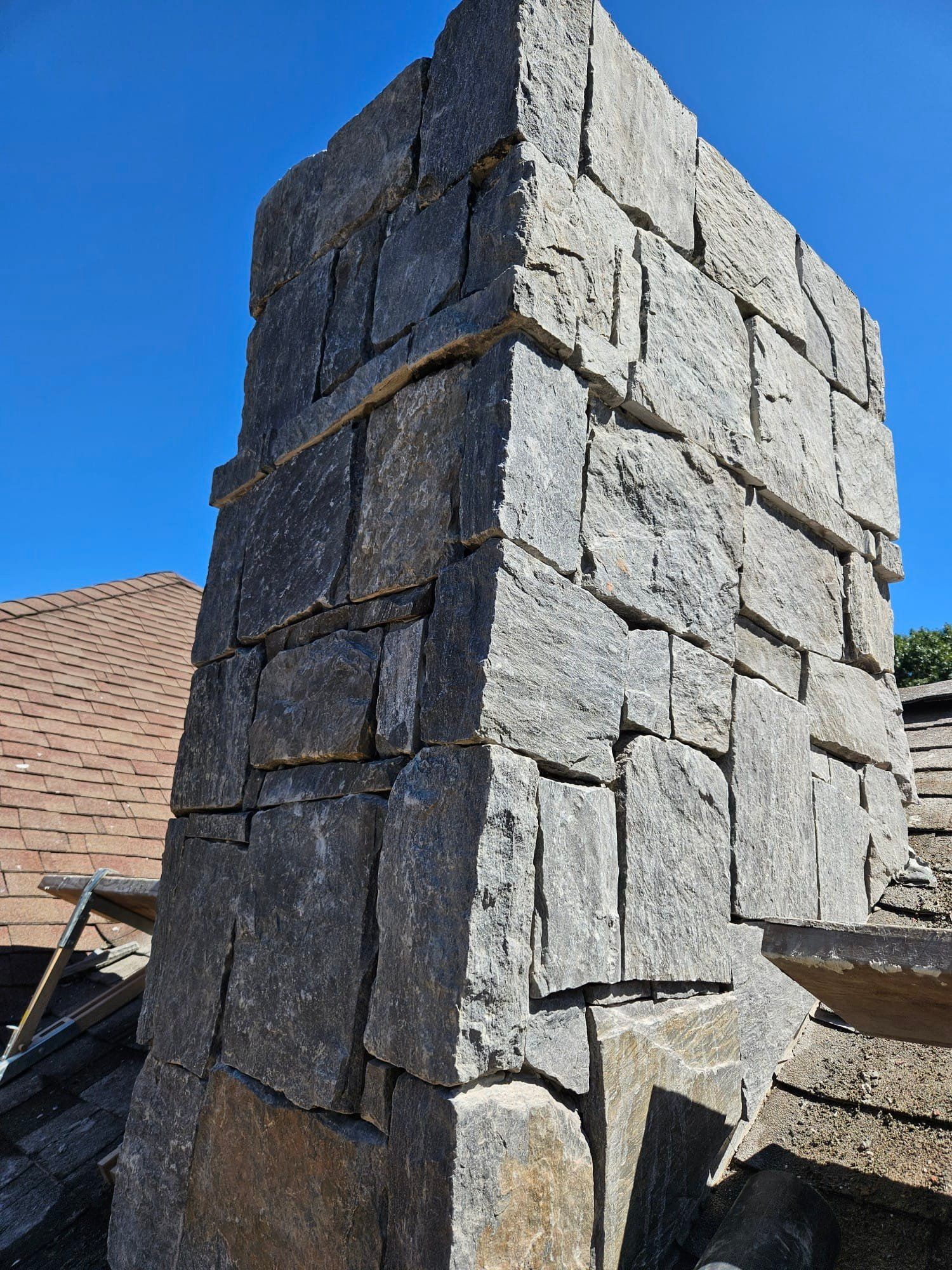 Stone chimney on a rooftop against a clear blue sky.