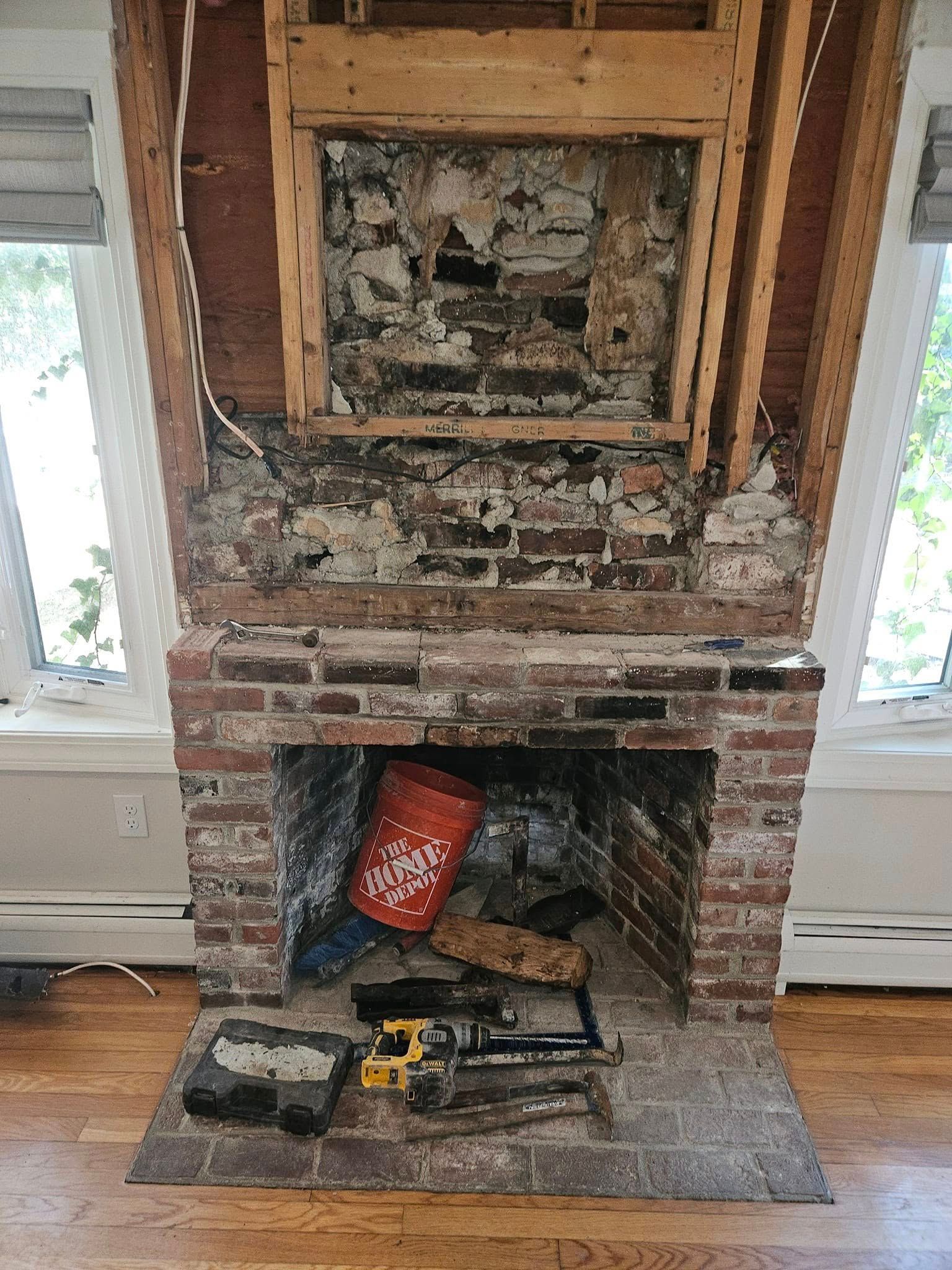 Brick fireplace with exposed interior and debris inside; tools on the hearth.