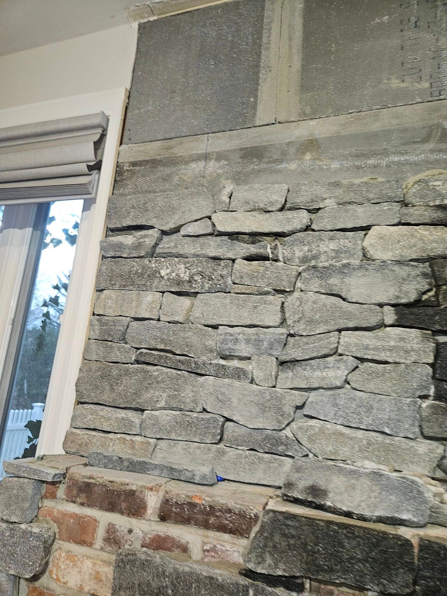 Stone fireplace with irregular gray stone, red brick base, and gray slate top section.