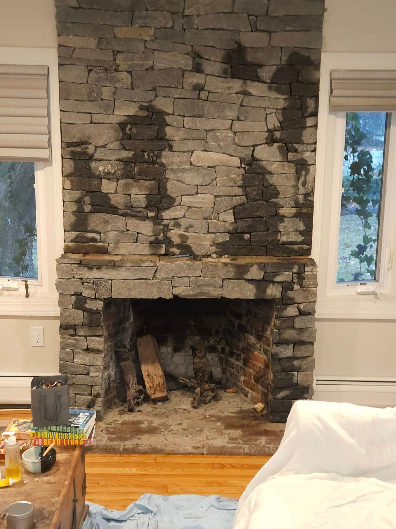 Stone fireplace with dark wet patches, two windows on each side.