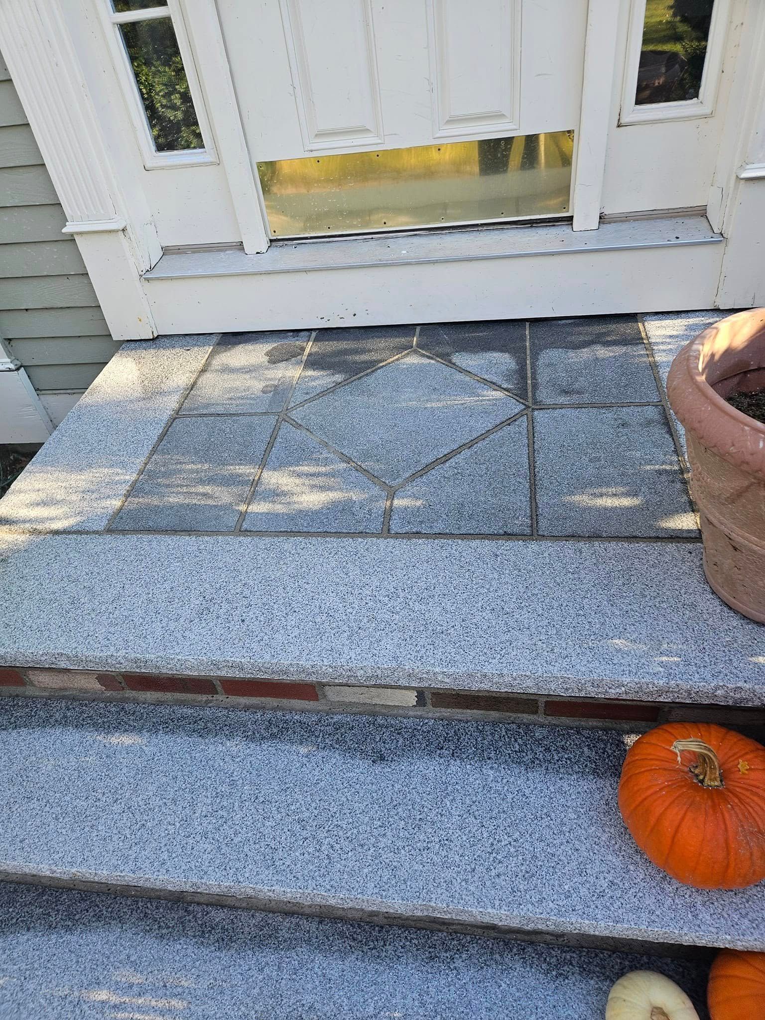 Stone steps leading to a front door with a pumpkin, featuring a decorative tiled landing.