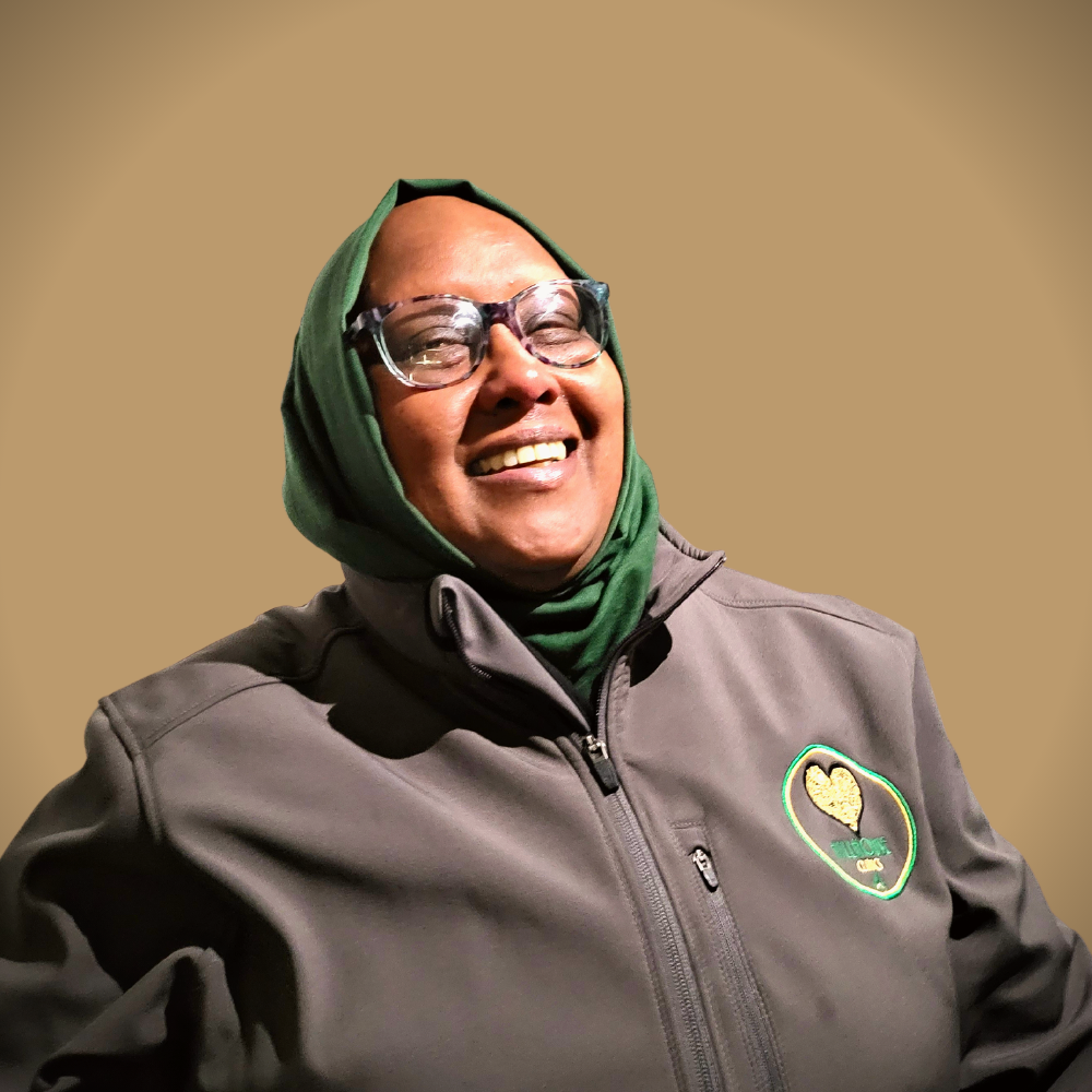 Een vrouw met een bril en een groene sjaal lacht