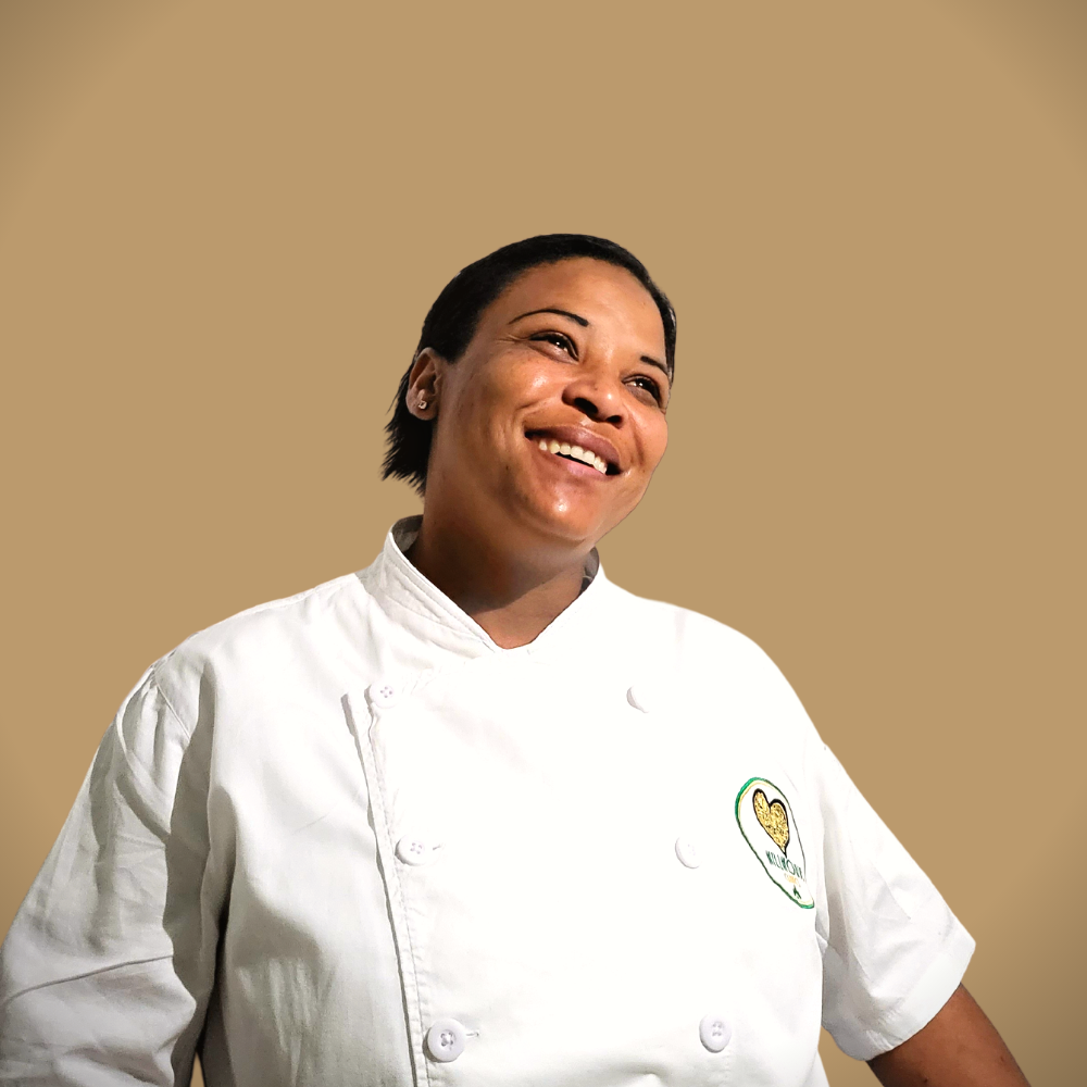 Een vrouw in een koksuniform lacht en kijkt omhoog