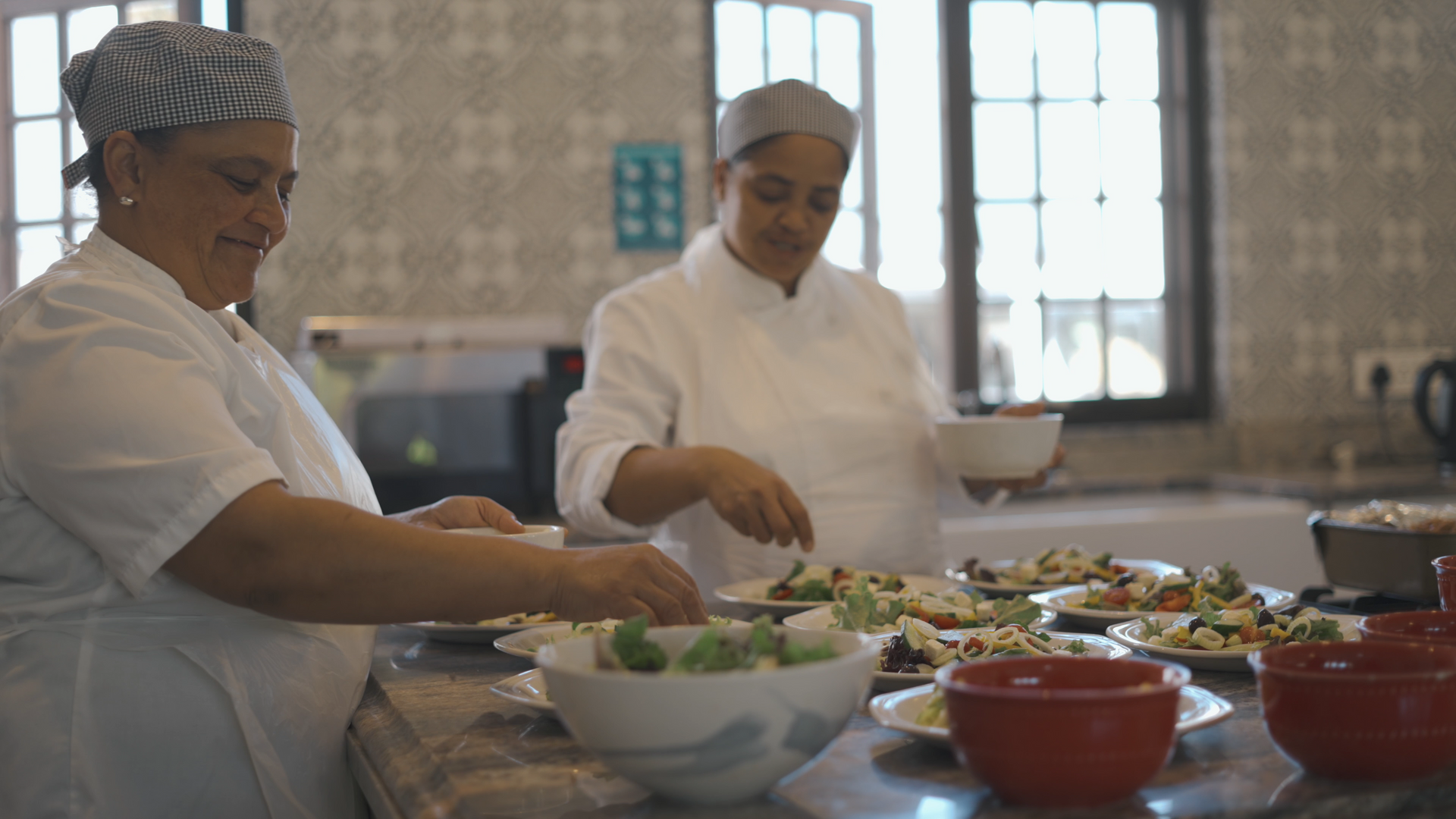 Twee vrouwelijke chef-koks bereiden eten in een keuken.