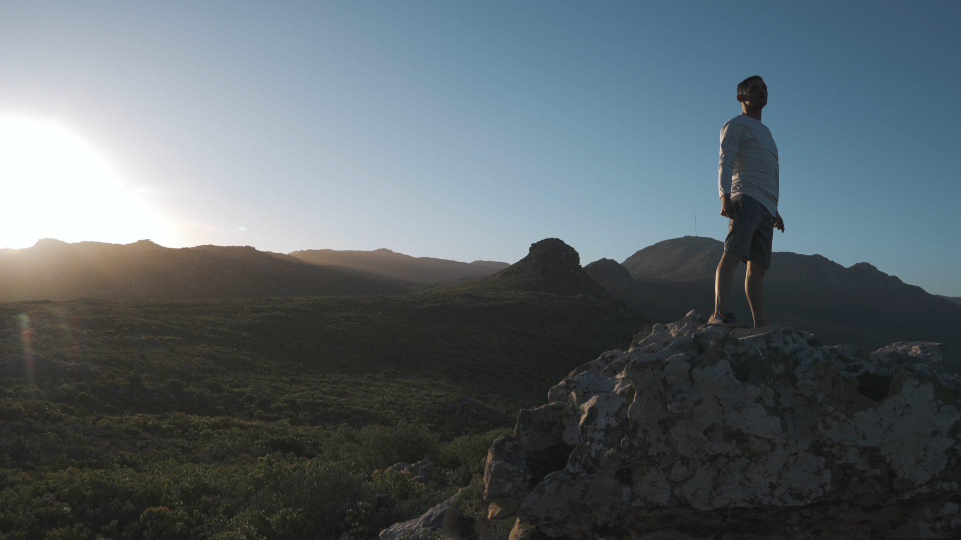 Een man staat op de top van een rotsachtige heuvel.