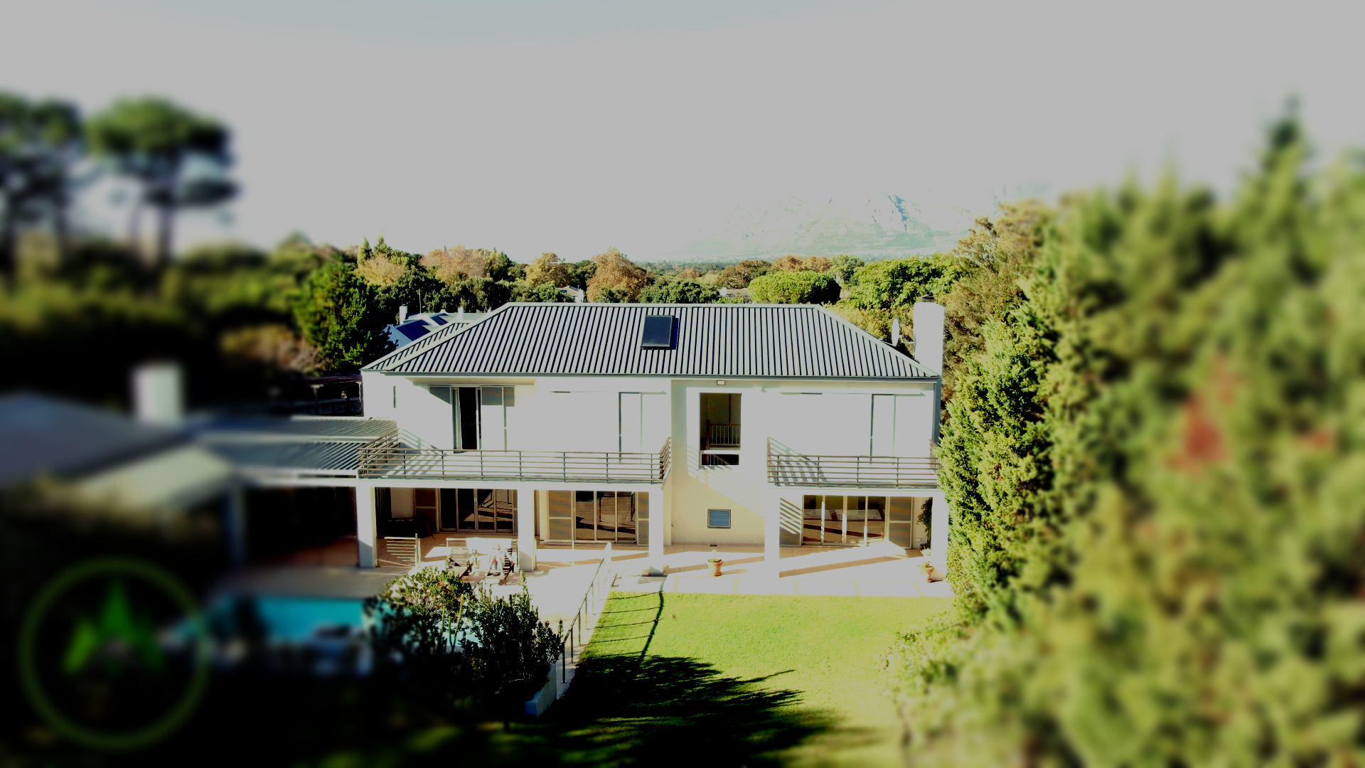 Een luchtfoto van een groot wit huis omgeven door bomen.