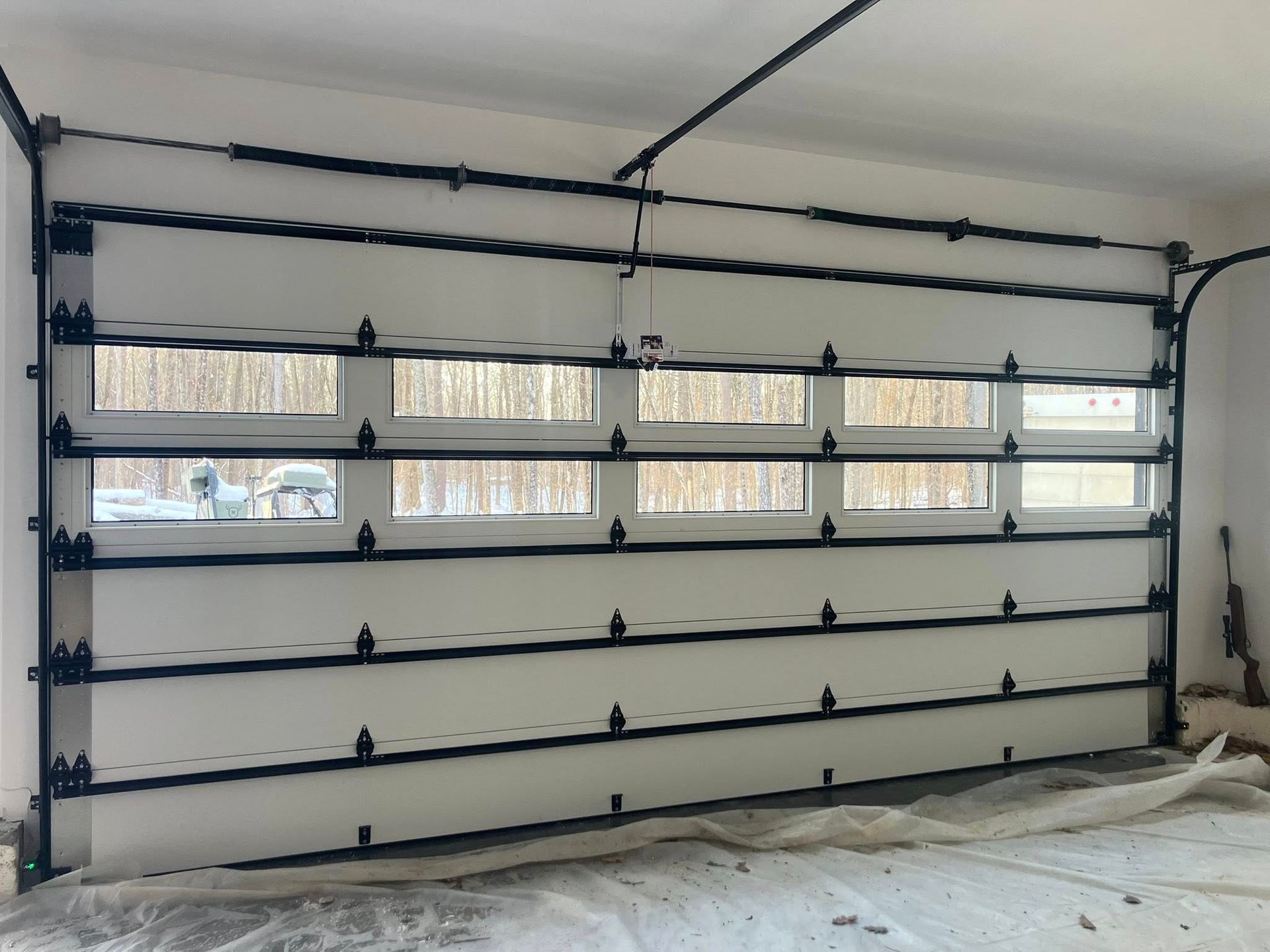 White and black garage door with windows, installed in a room.