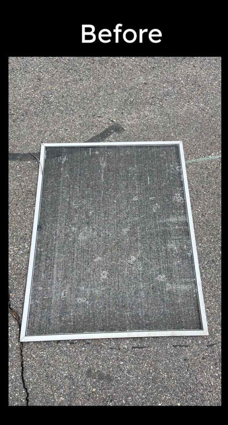 A screen door is sitting on the ground before being cleaned.