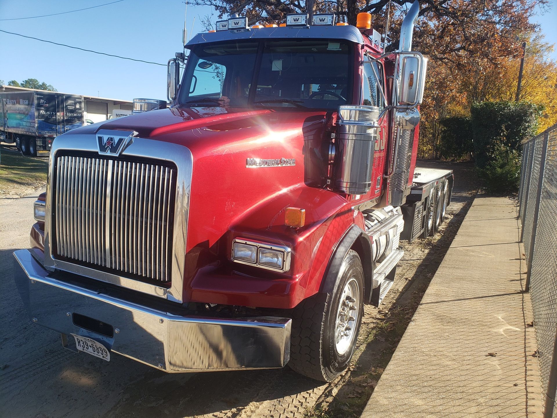 Red Western Star semi-truck parked outdoors, shiny grill, chrome accents, sunny day.