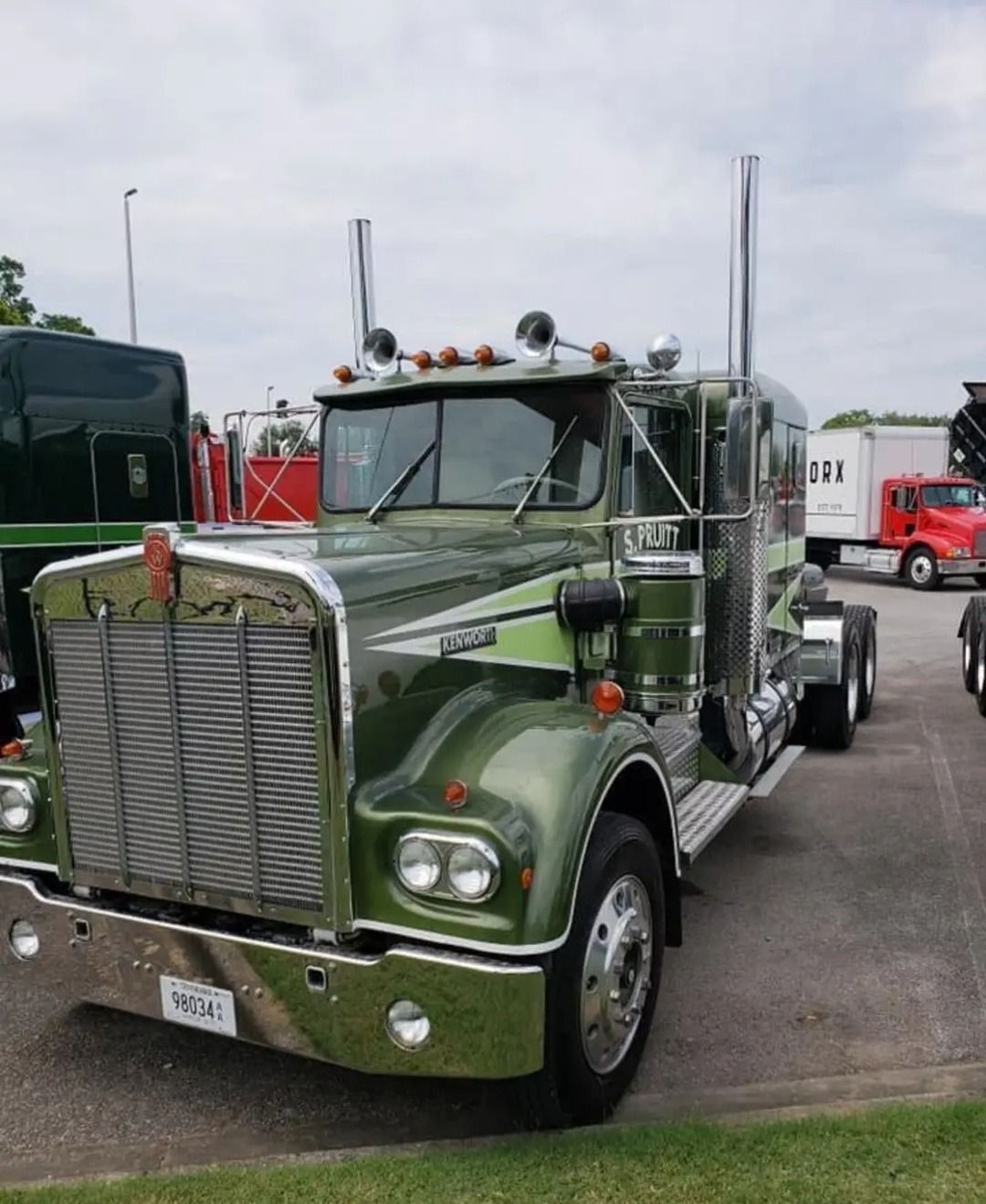 Green vintage Kenworth semi-truck with chrome accents parked outdoors.