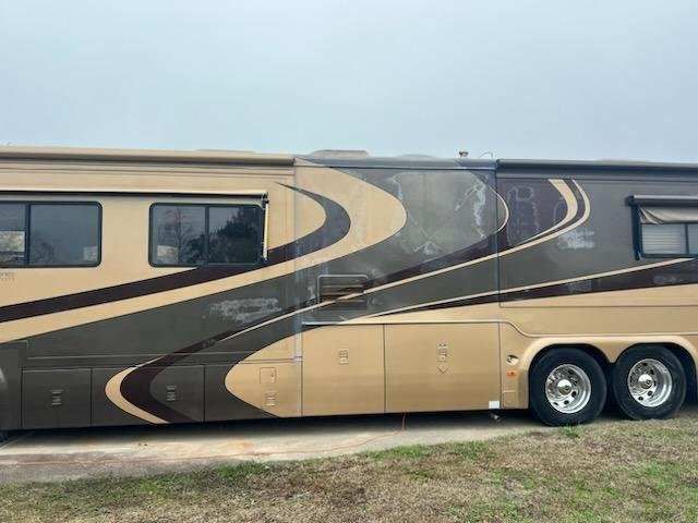 Brown and tan RV parked outside with decorative swirls.
