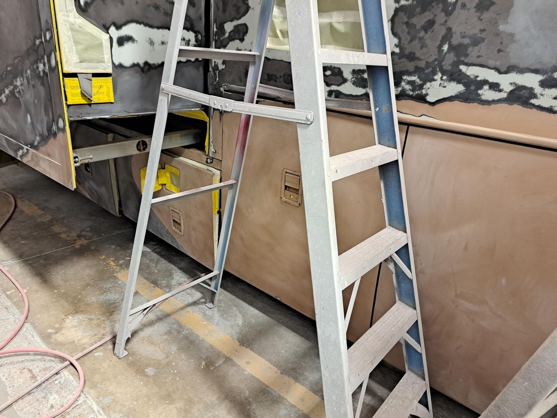 Gray step ladder next to a partially disassembled vehicle.