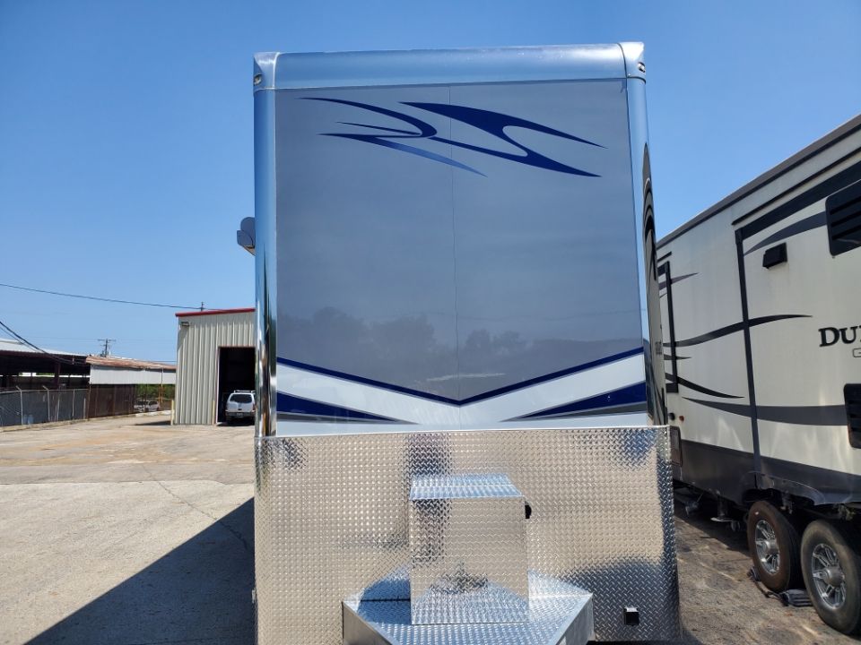 Silver and gray trailer with blue accents, diamond plate base, against a bright sky.