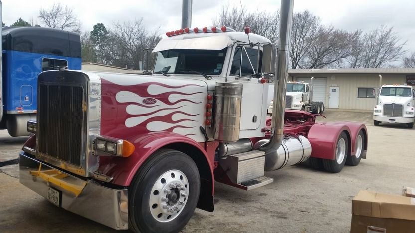 White and red Peterbilt semi-truck with flame graphics parked outside a building.