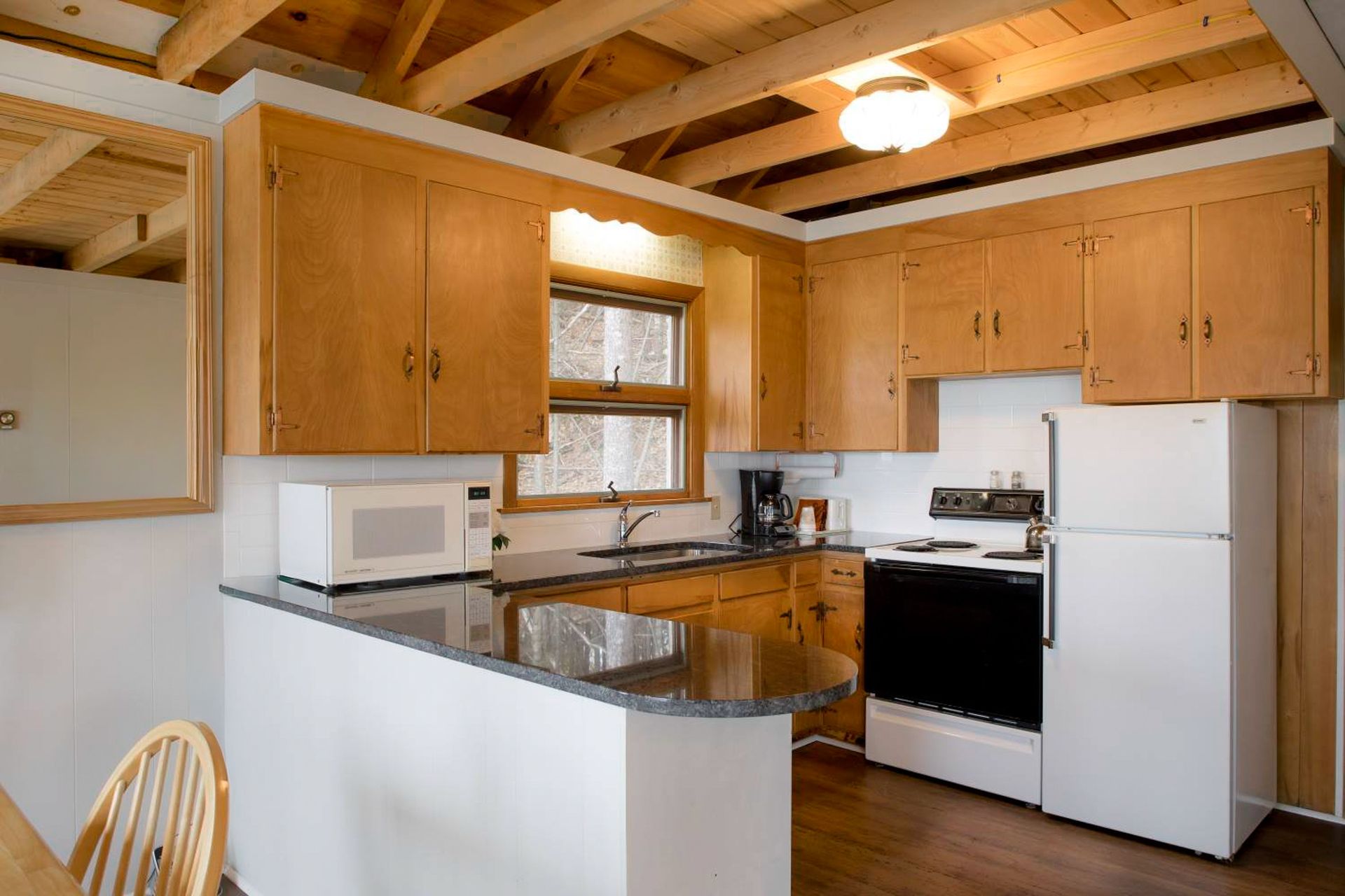 Small kitchen with light wood cabinets, appliances, and a dark countertop.