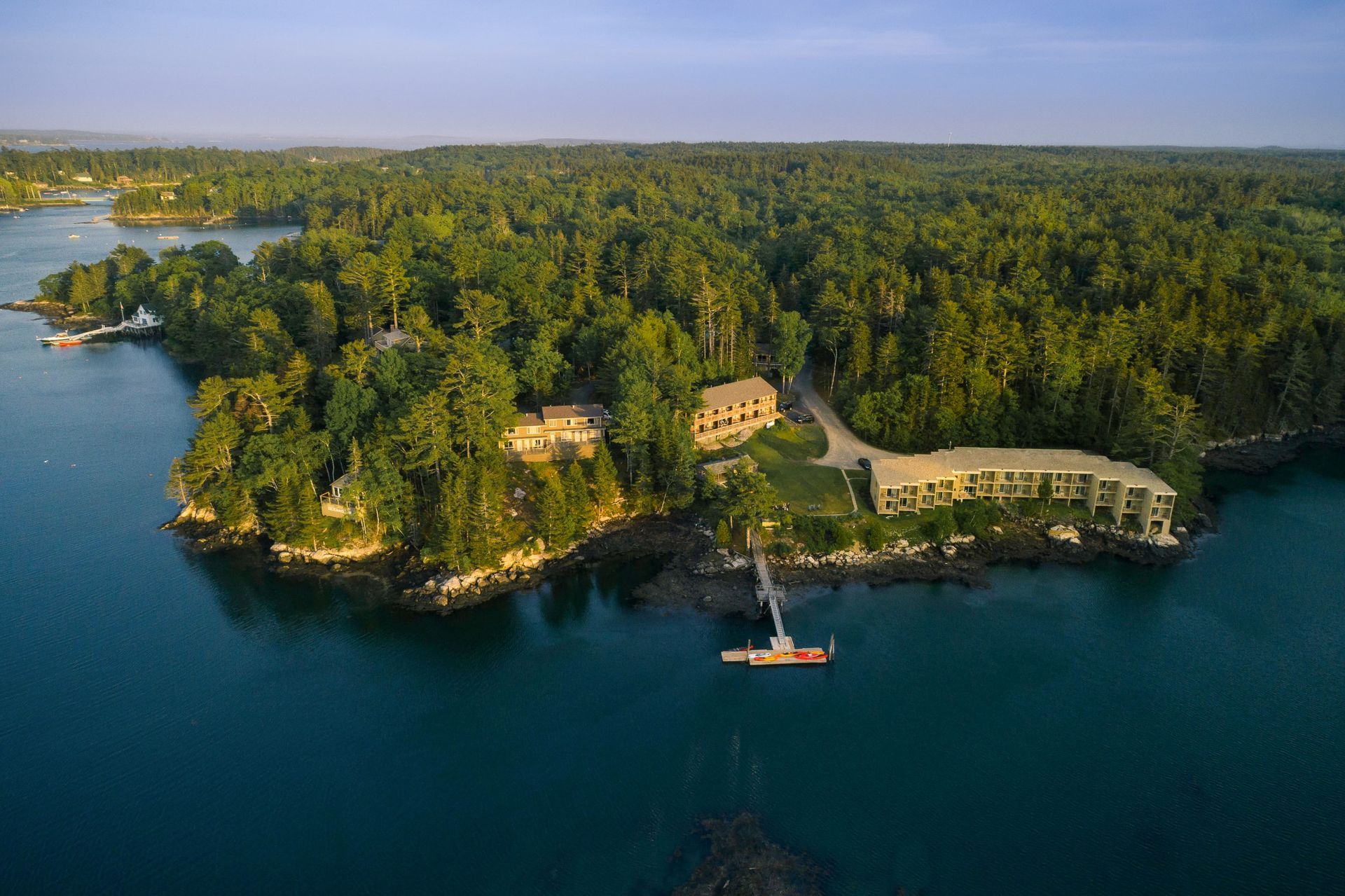 Aerial view of a lush green island with buildings and a dock surrounded by blue water.