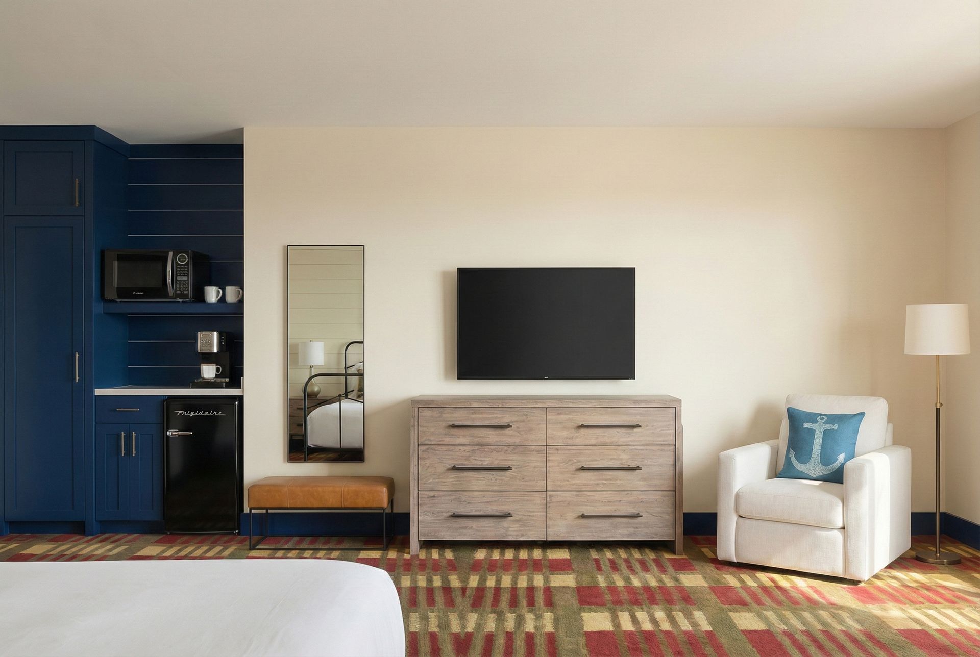 Hotel room with blue cabinet, TV, dresser, chair, and a bed.