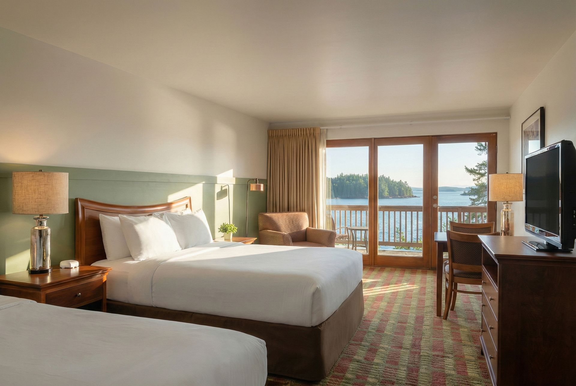 Hotel room with two beds, a desk, and a balcony overlooking a lake.