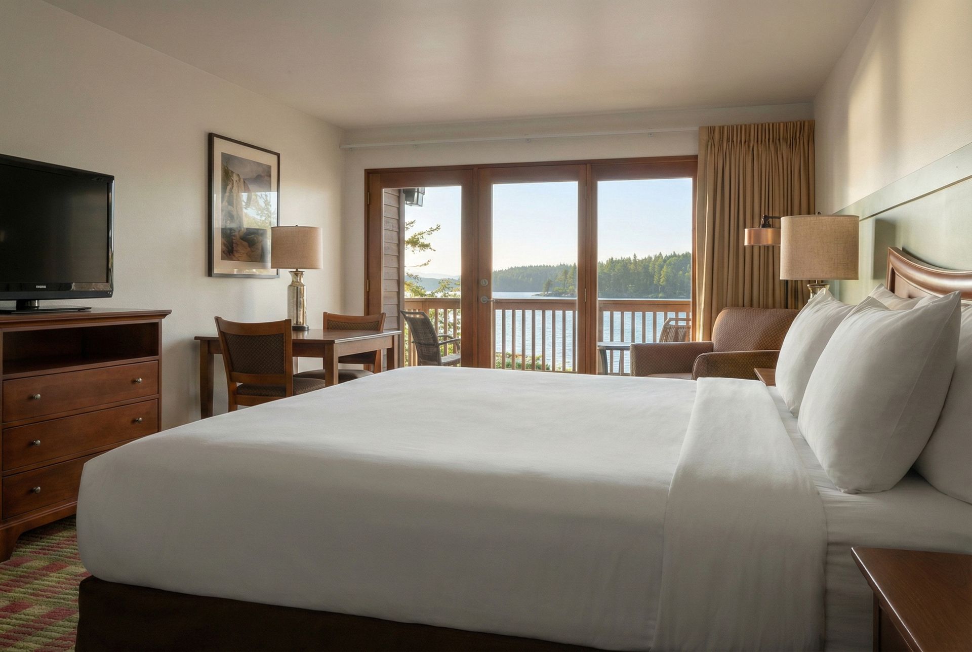 Hotel room with a large bed, wooden furniture, and a balcony overlooking water.