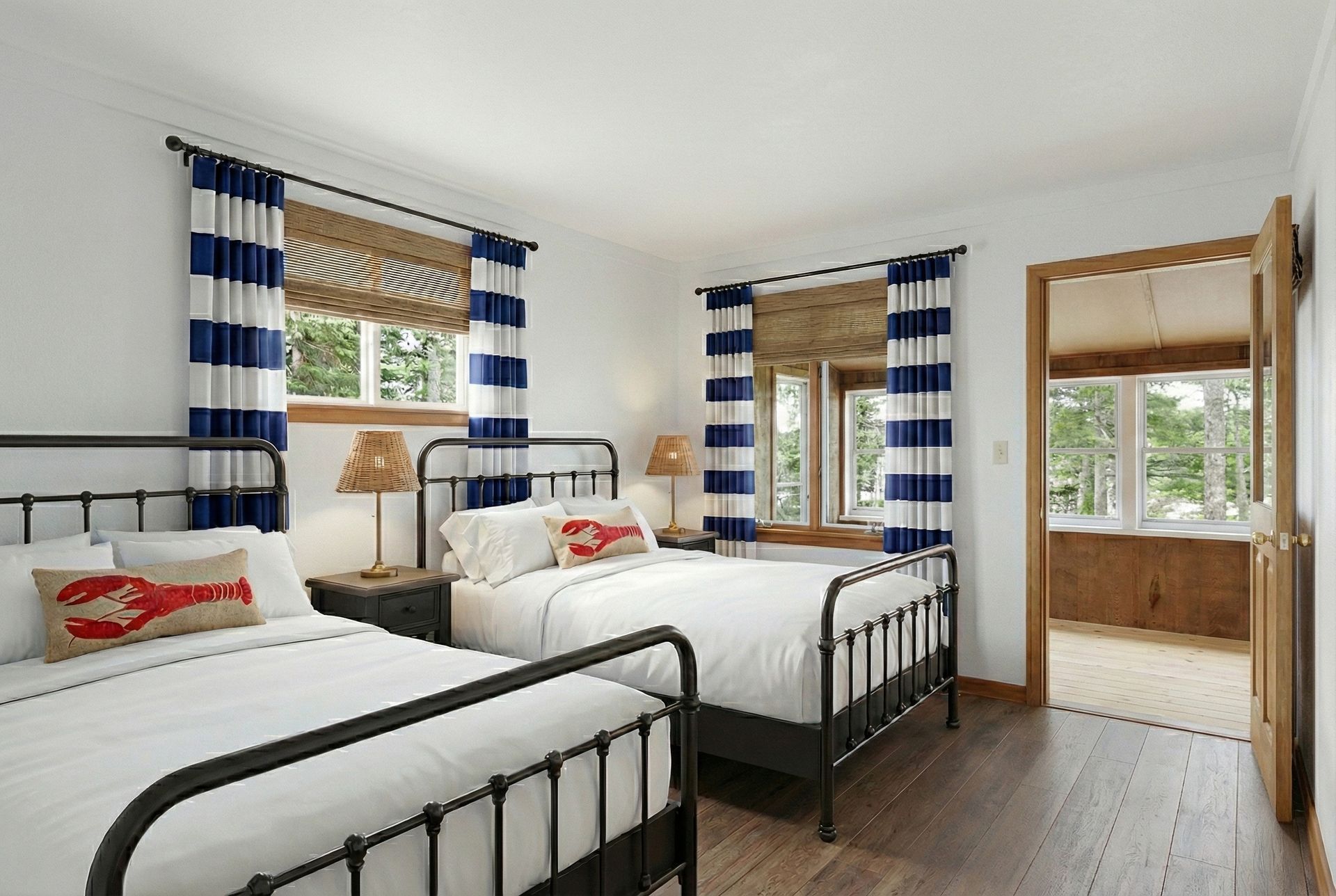 Bedroom with two beds, nautical theme: white walls, blue-striped curtains, wood floors, and a view into a bathroom.