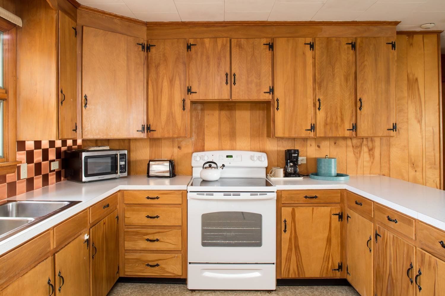 Kitchen with wood cabinets, white countertops, and white stove.