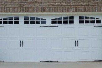White garage door with arched windows and black hardware.