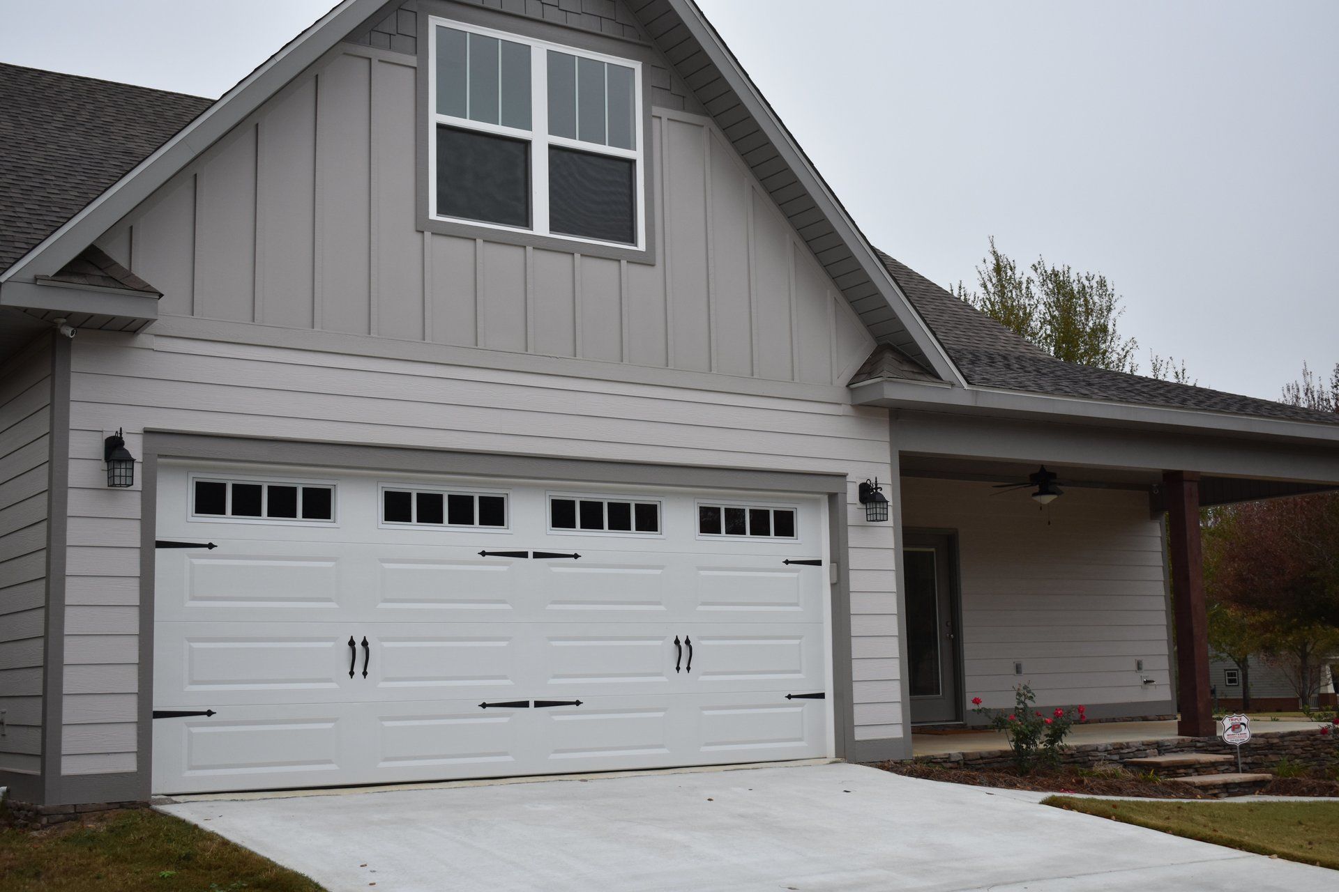White garage door on a light gray house with dark accents. Concrete driveway in front.