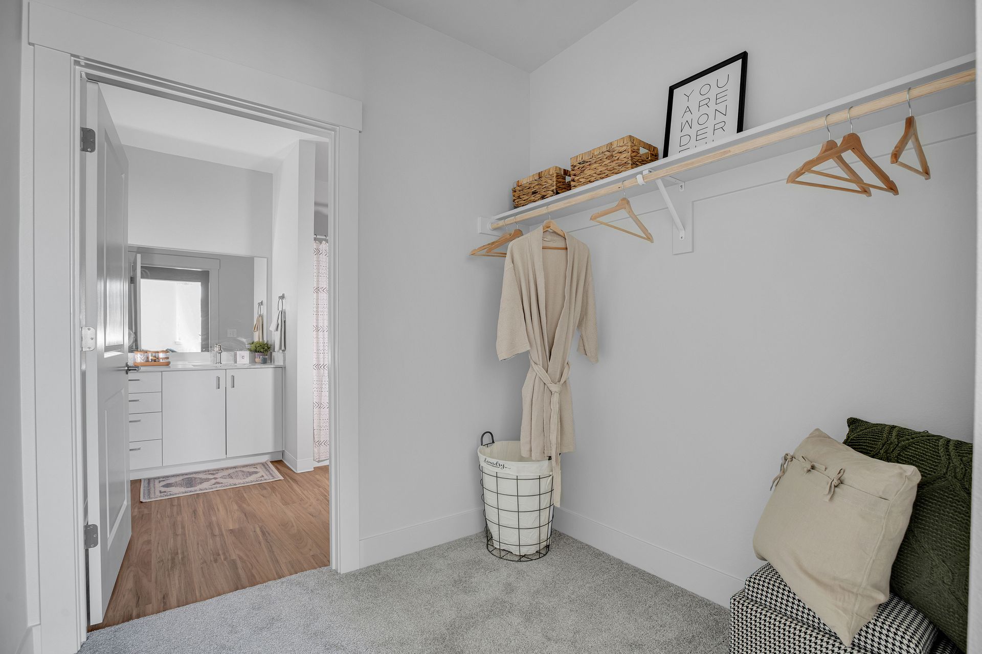 A walk in closet with a shelf and clothes hanging on it.