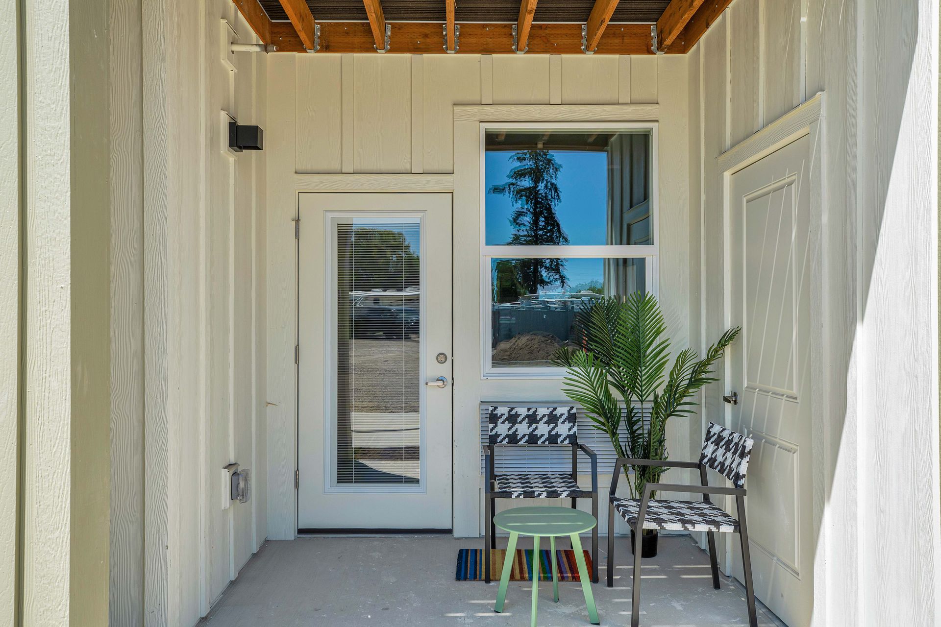 A white house with a porch with chairs and a table.