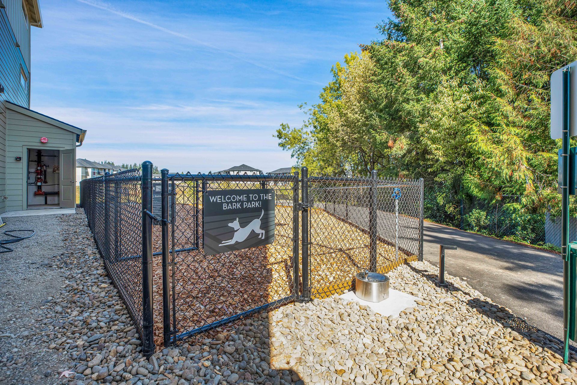 A dog park with a fence and a sign that says `` welcome to the dog park ''.