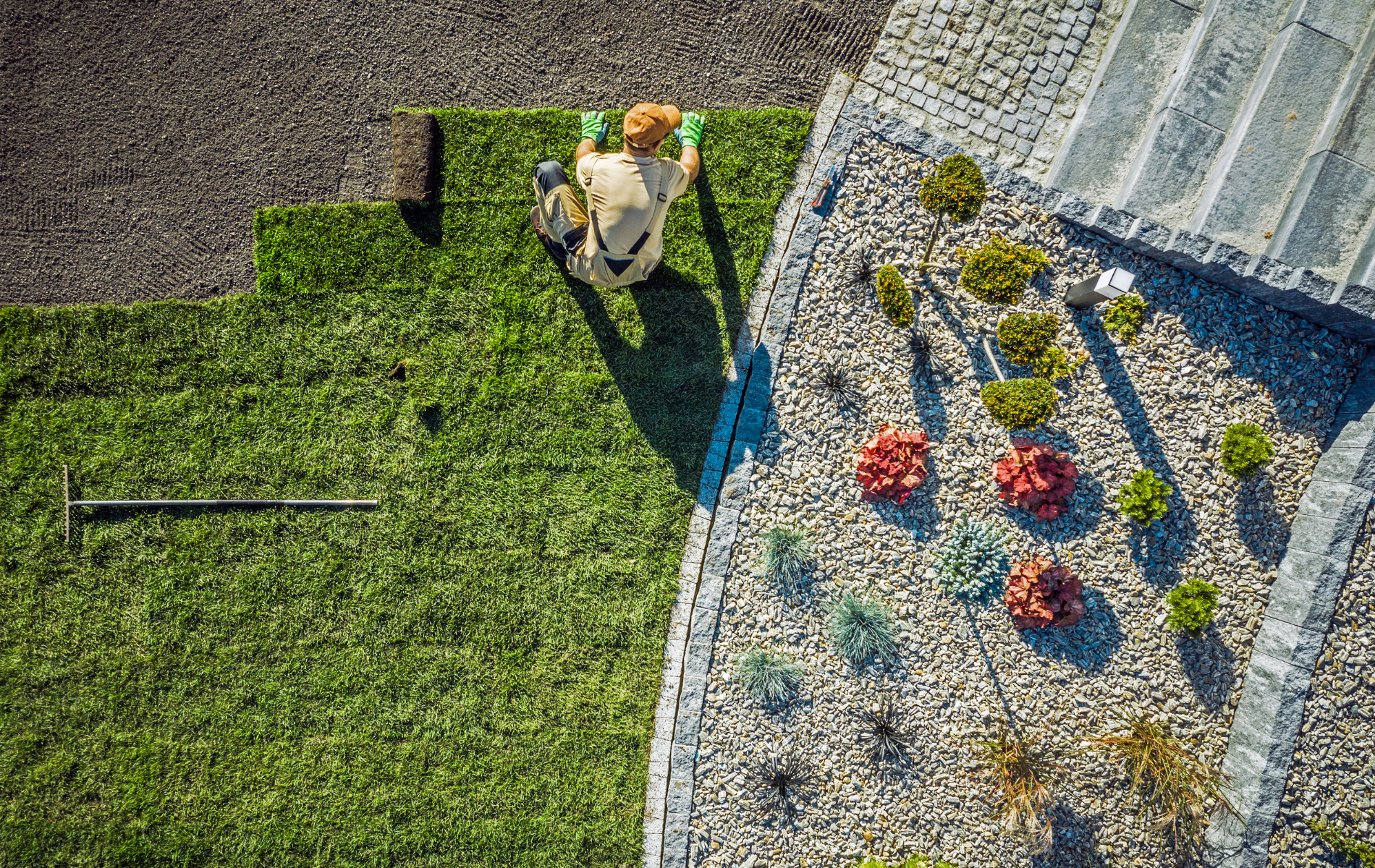 An aerial view of a man laying turf on a lawn.