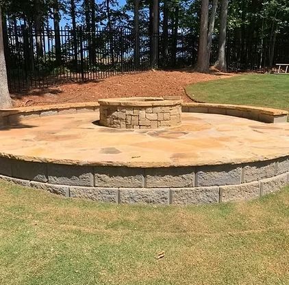 A fire pit is sitting in the middle of a lush green field.