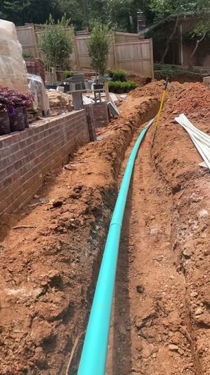 A green pipe is being installed in the dirt.