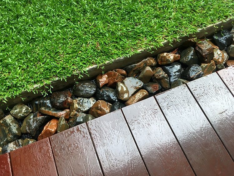 A wooden deck with rocks and grass in the background