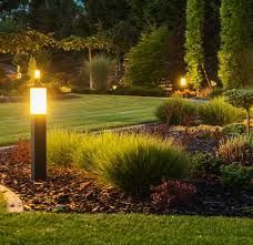 A garden with a lamp post in the middle of it at night.