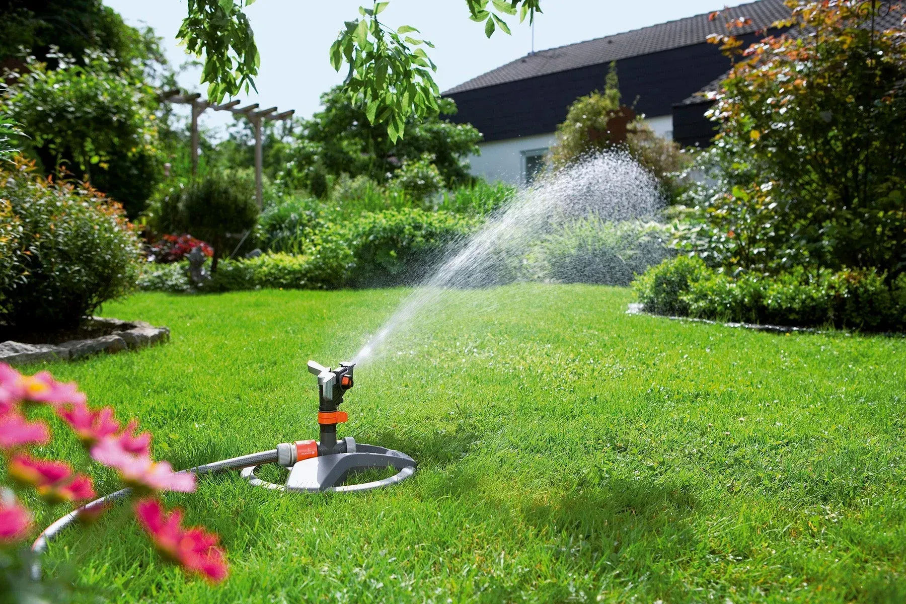 A lawn sprinkler is spraying water on a lush green lawn.